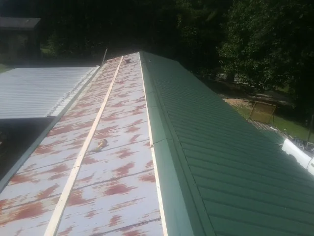 Old rusted panels beside newly installed green metal roofing — Wind Damage Roof Repair by Roofing Brothers in Llano