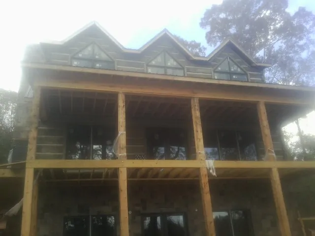 Dormers and porch framing on a large log home under construction — Roof Coating work by our crew in Llano