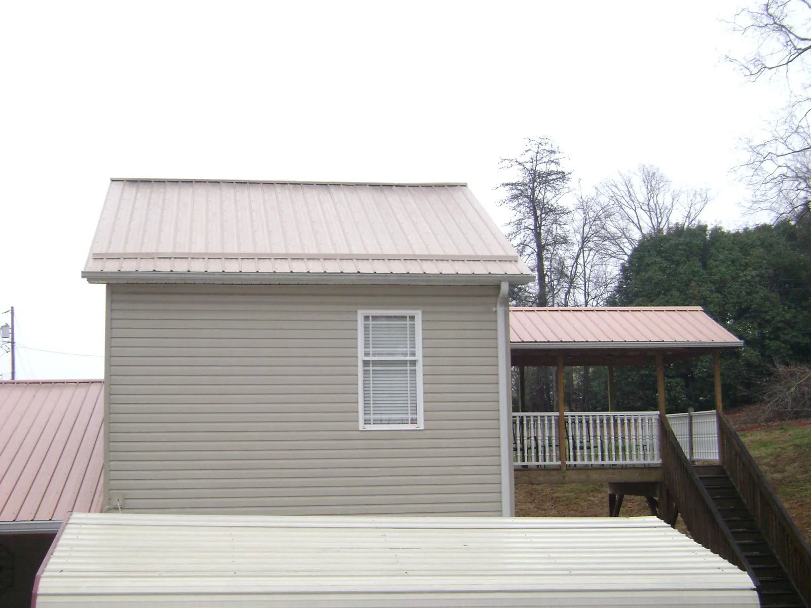Tan metal roofs on a two story addition and attached porch, from a Roof Replacement job in Llano